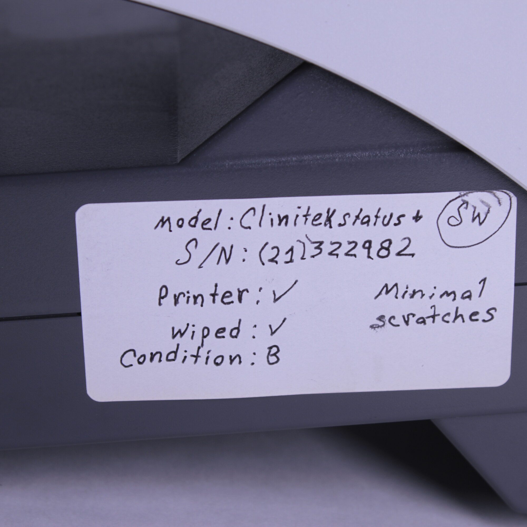 Close-up of handwritten condition label for Siemens Clinitek Status+ analyzer with serial number (21)322982 and test notes