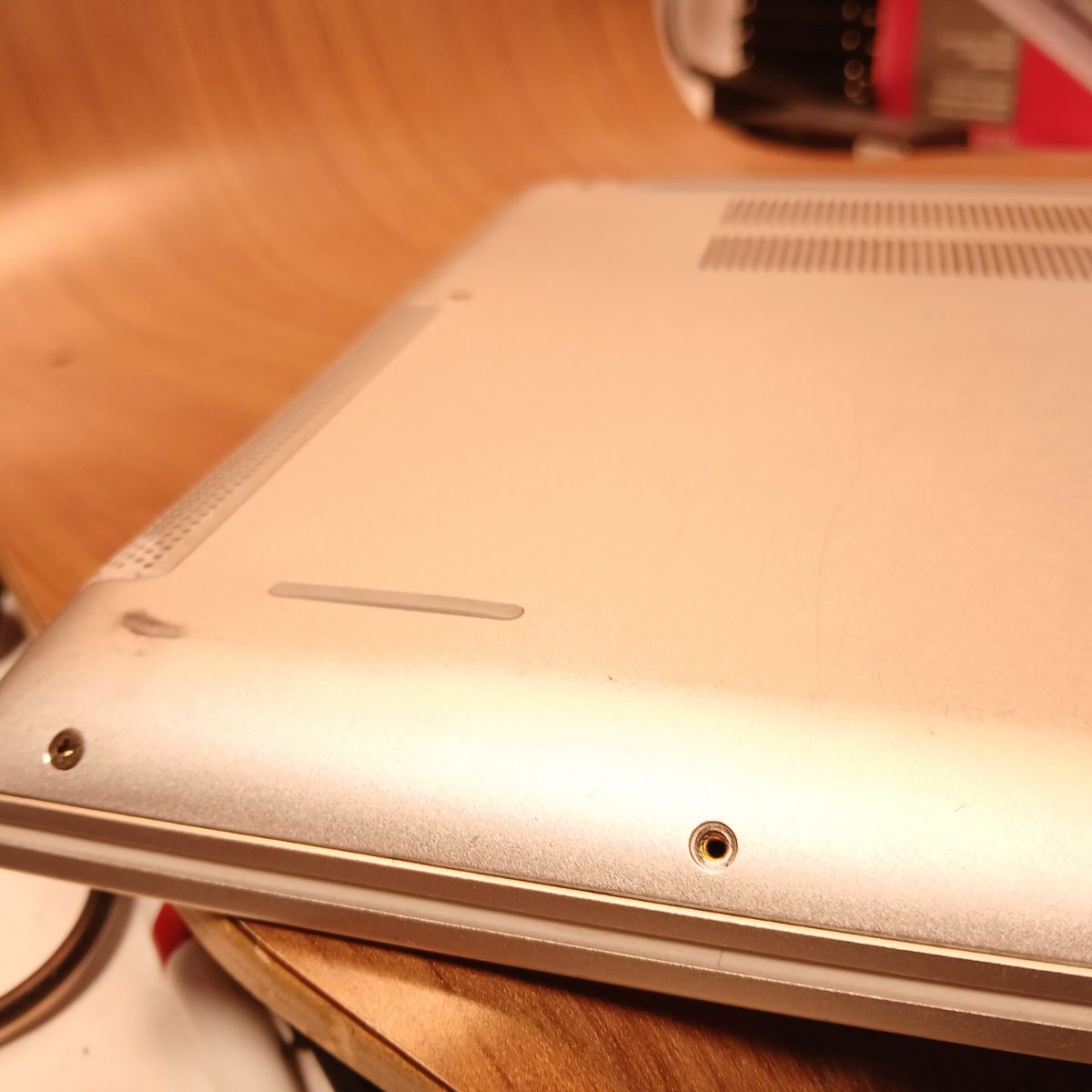 Bottom corner close-up of Dell Inspiron 15 7501 showing cosmetic wear and screw mount